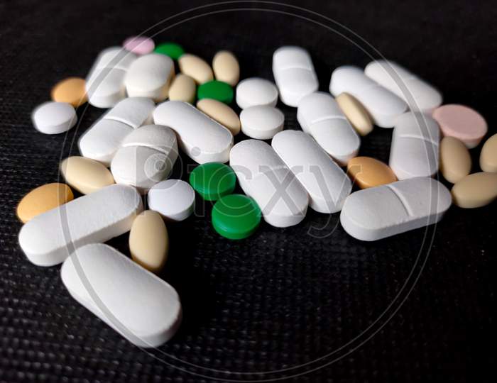 Close Up Of Bunch Of Medicine Tablets Or Pills On Desk.