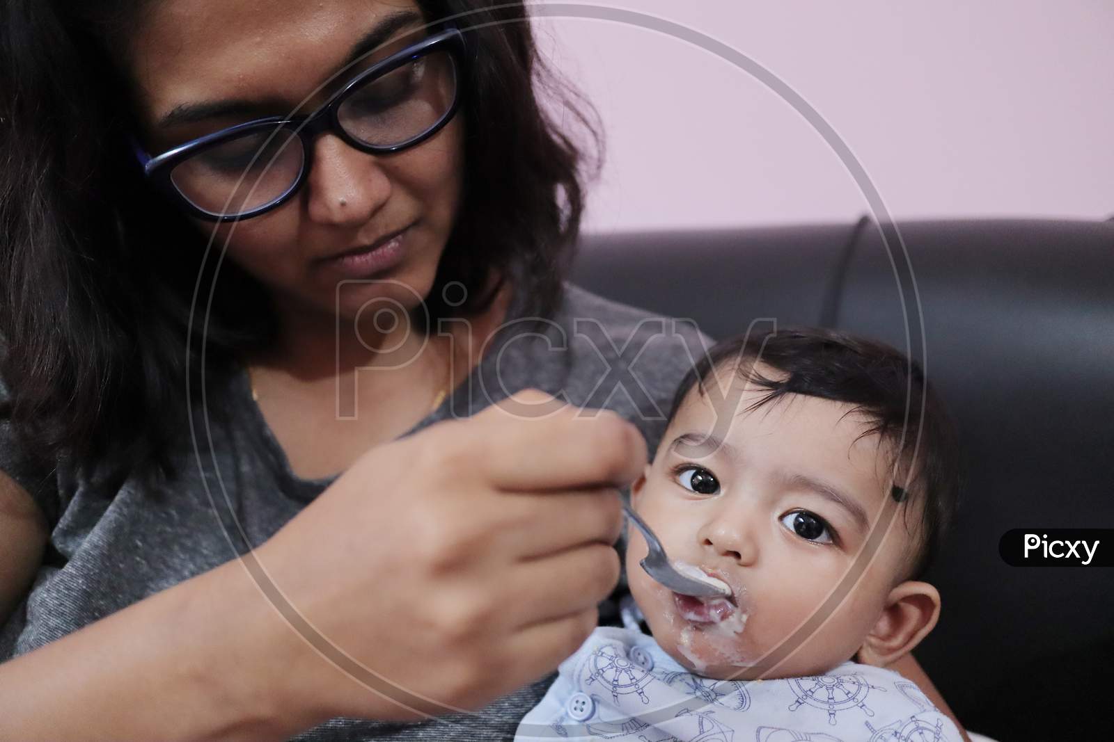 An Indian Mothher Feeding Milk To A Baby Boy With A Spoon