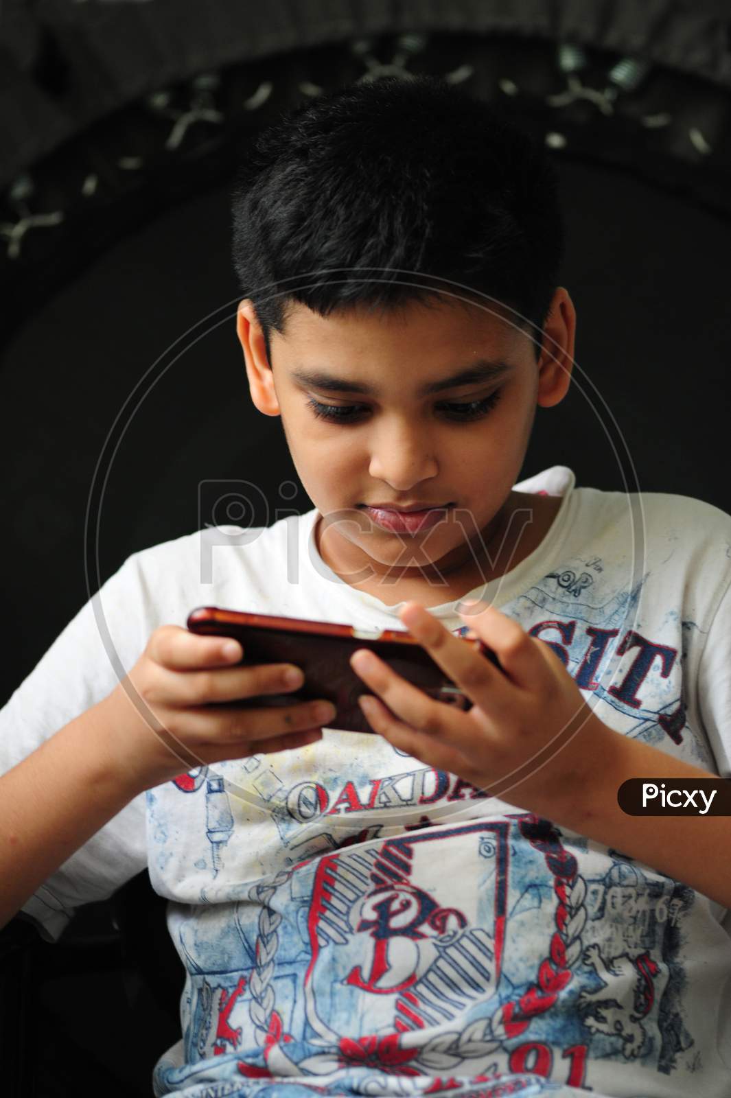 Boy engrossed in playing a game on a mobile phone