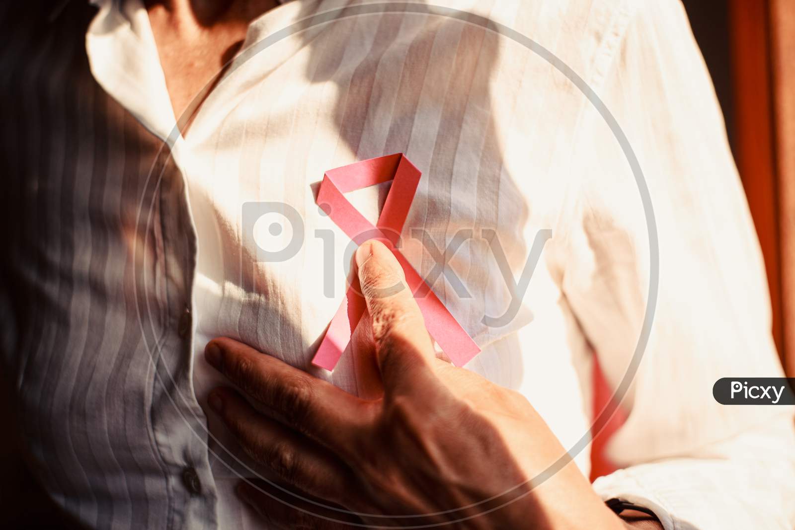 An Horizontal Shot Of A Old Woman Pointing Pink Ribbon On Chest From Below
