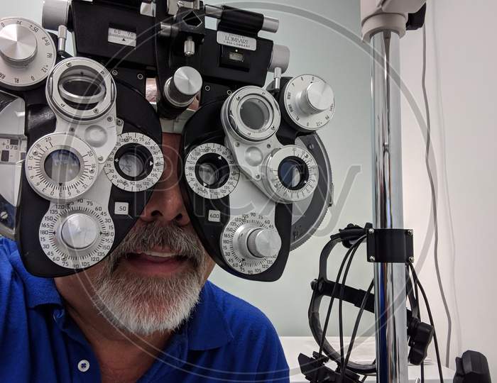 Man With Goatee Wearing Blue Shirt Gets Eye Exam With Diopter Machine