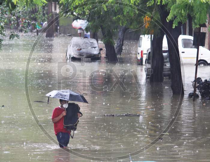 A man walks through a waterlogged road during rains, in Mumbai, India on August 4, 2020.