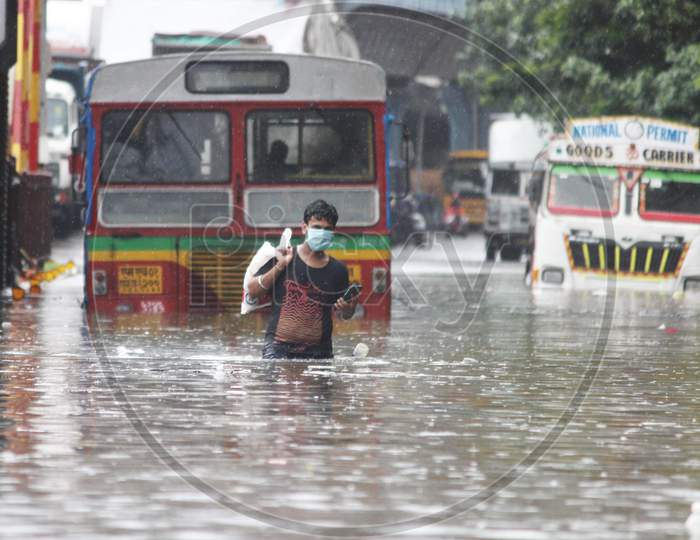 A man walks through a waterlogged road during rains, in Mumbai, India on August 4, 2020.