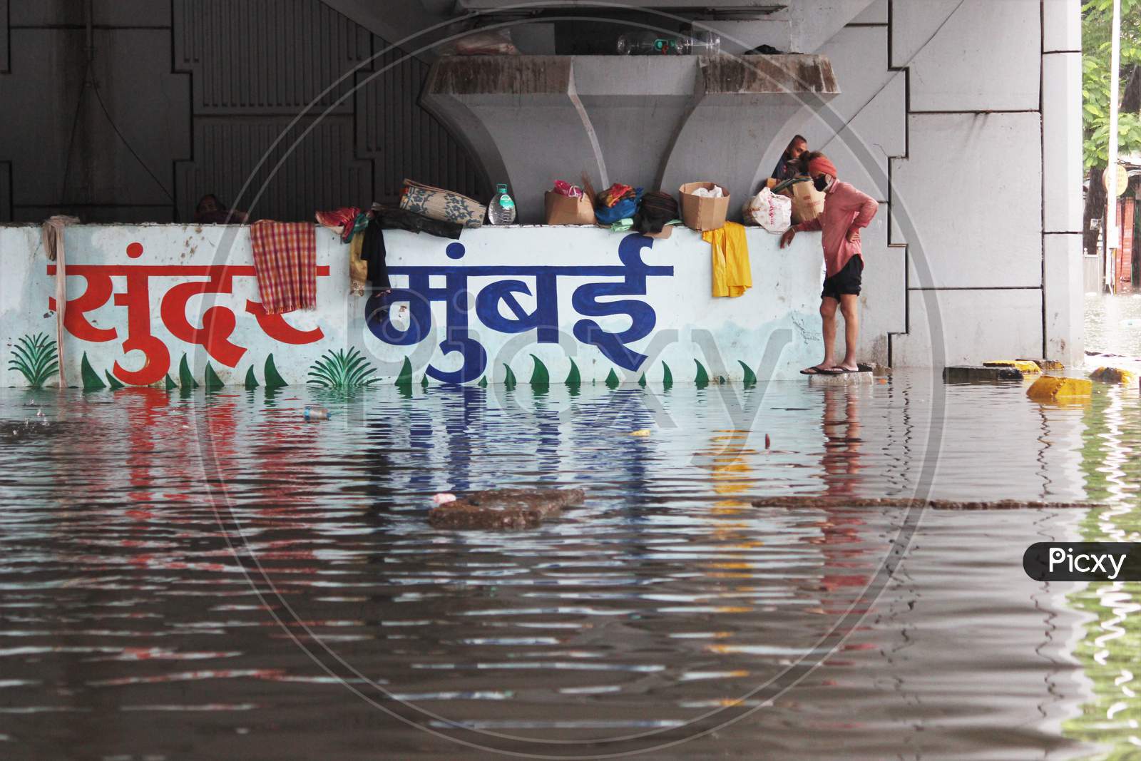 A man stands on the corner under a bridge that is waterlogged, during rains, in Mumbai, India on August 4, 2020.