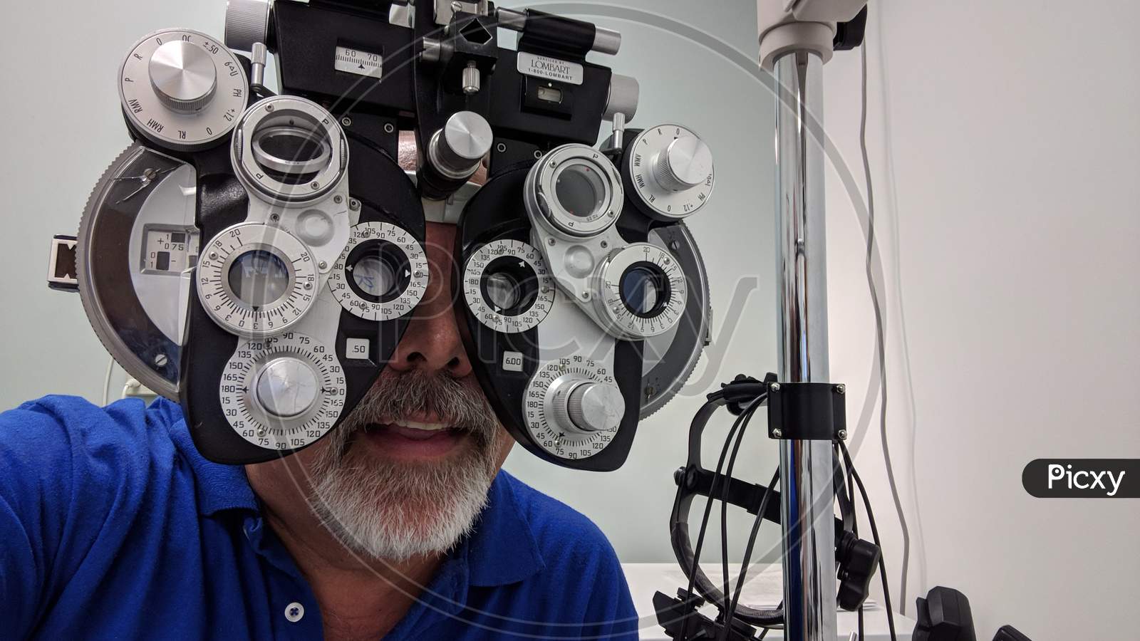 Man With Goatee Wearing Blue Shirt Gets Eye Exam With Diopter Machine