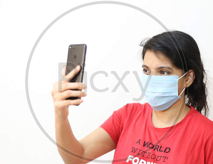 Work From Home Concept, Young Girl With Mask And Mobile In White Isolated Background