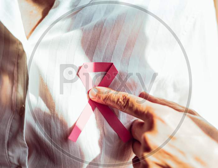 An Horizontal Shot Of A Old Woman Pointing Pink Ribbon On Chest