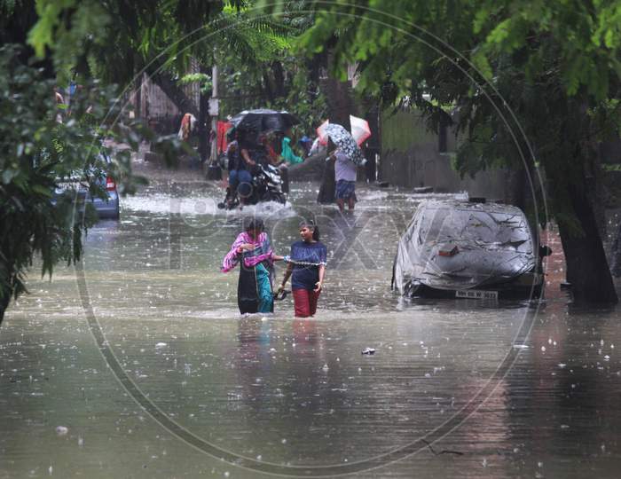 People walk through a waterlogged road during rains, in Mumbai, India on August 4, 2020.