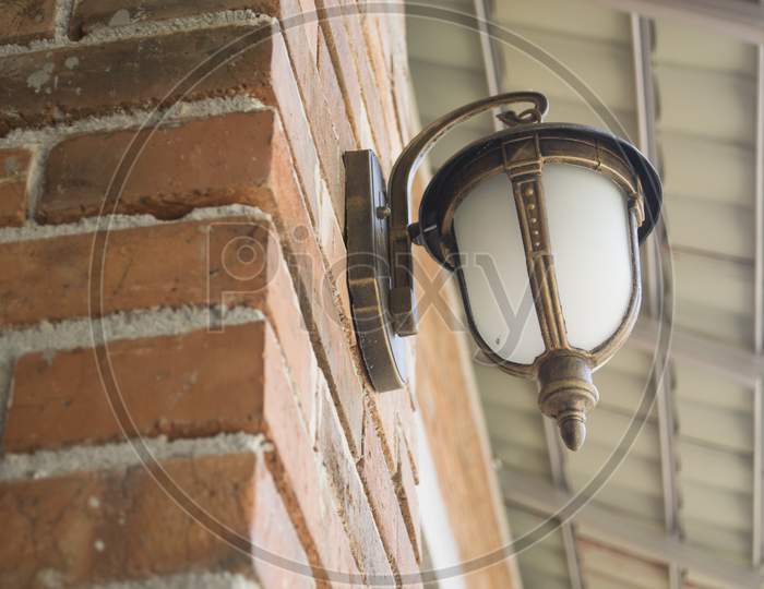 Brown Decorative Electric Lamp Mounted On A Brick Wall
