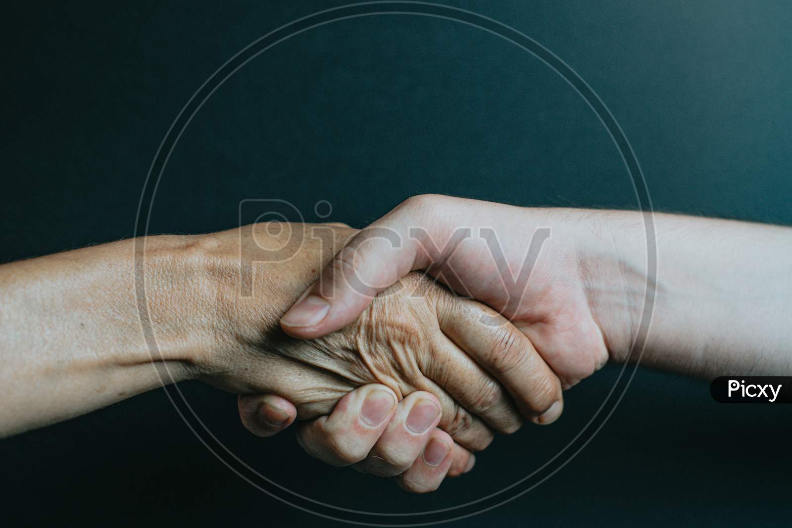 An Old Person And A Younger One Shaking Hands
