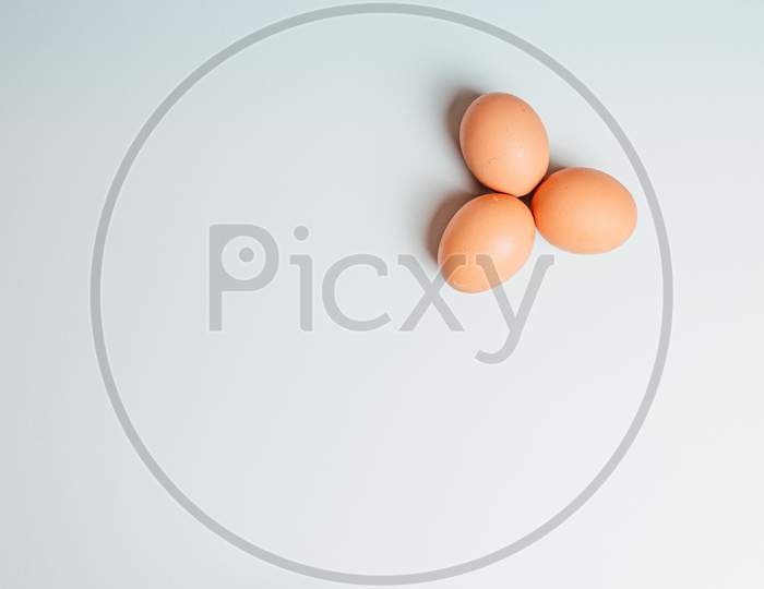 White Background With Three Eggs In A Corner