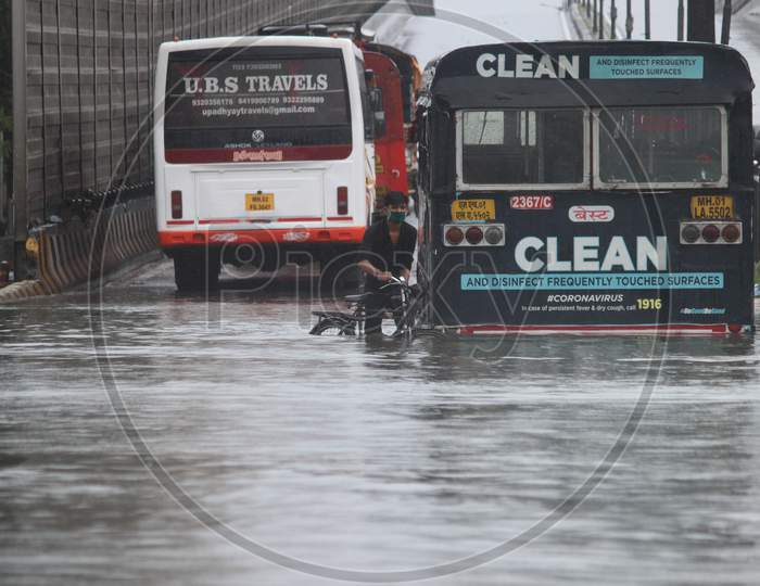 A man walks with his cycle on a waterlogged road during rains, in Mumbai, India on August 4, 2020.