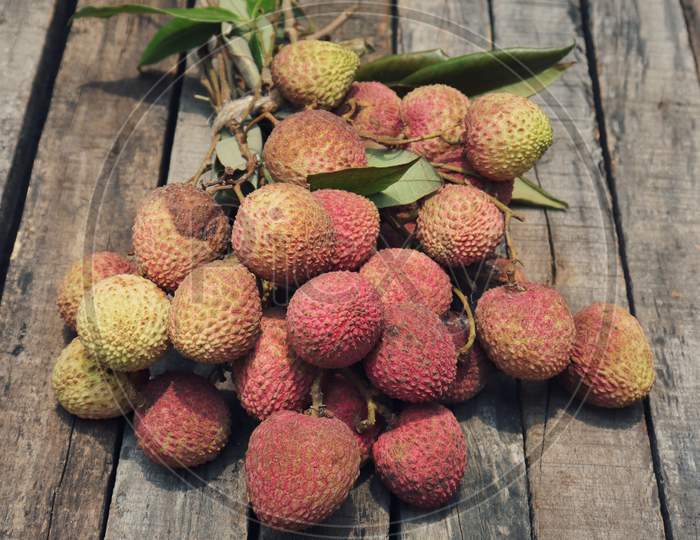 Organic Lychee Or Litchi Cluster With Leaves Isolated On Wooden Background In Vertical Orientation