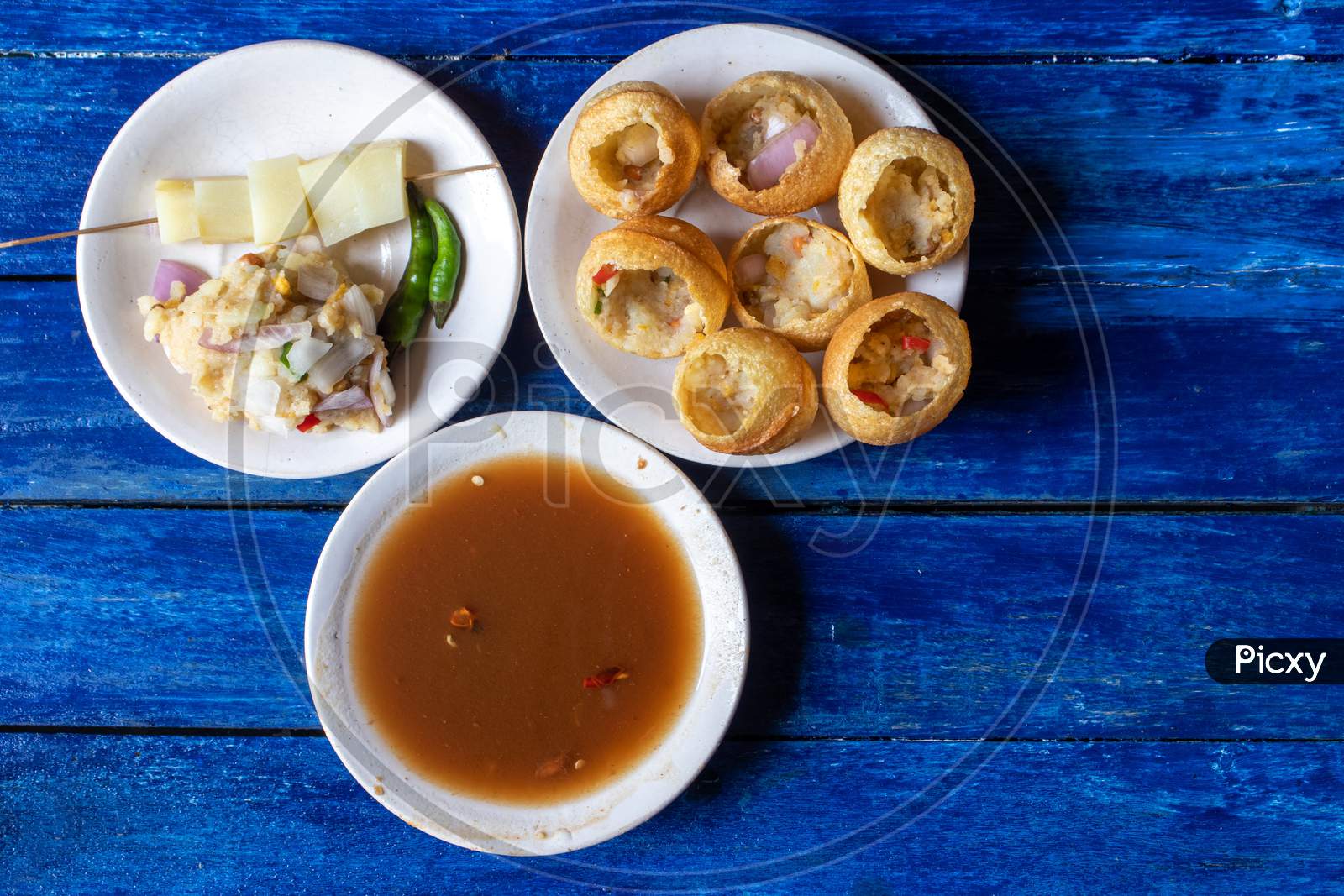 Panipuri Or Golgappa With Tamarind Chutney, Chili And Spicy Potato Stuff In Plates Isolated On Wooden Background, Also Known As Phuchka, Paani Patashi, Gup Chup