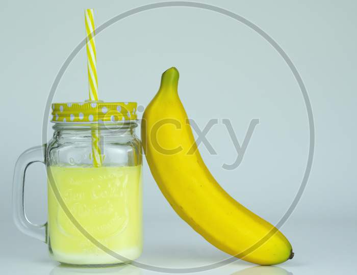 A jar with orange juice and a fresh banana in front for breakfast item