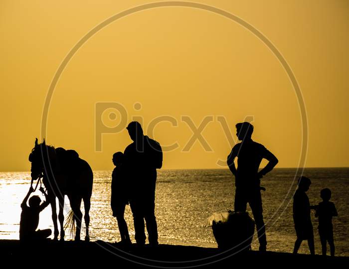 A Silhouette Of People And A Horse At Jampore Beach In Daman, India