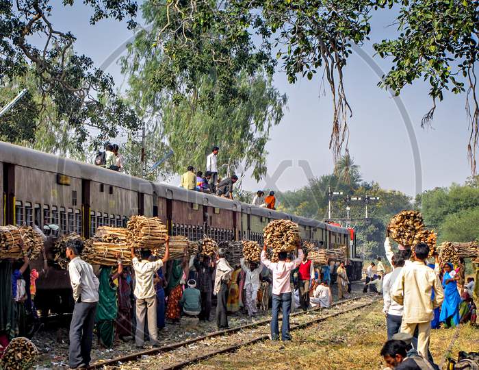 Local villagers with wood waiting for their train as pairing train waits for crossing.