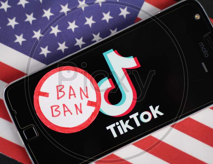 Maski, India - 4 August, 2020 : Tiktok Logo On Phone And Ban Stamp With America Flag Background.
