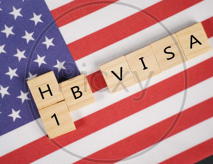 Concept Of H1B Visa For Foreign Workers Showing Wooden Letters With Us Or United States Flag As Background