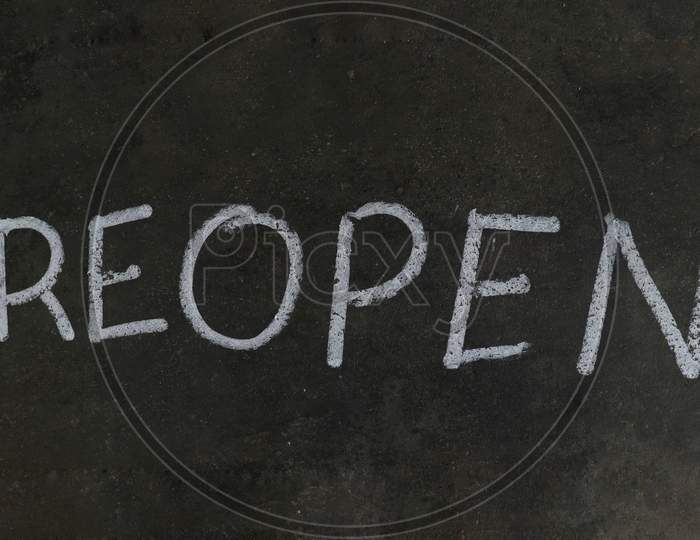 Reopen Word Written  With White Chalk On Black Surface