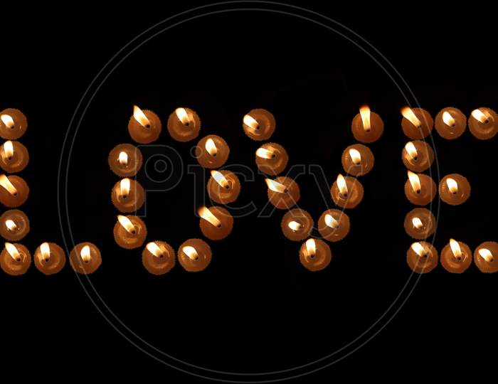 Love Word Written With Burning Candles In Black Background