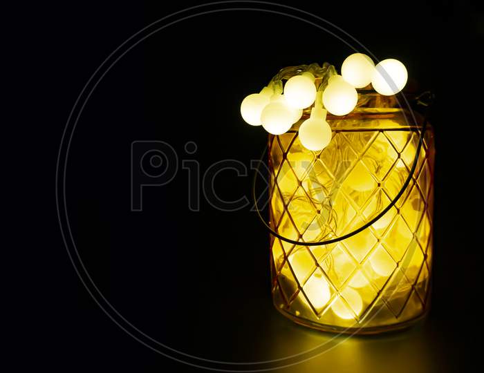 Glass jar with lit LED lights inside on dark horizontal background