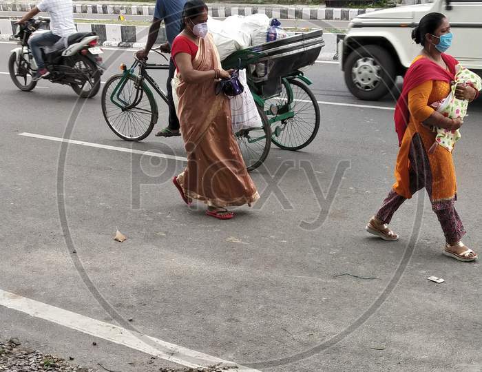 Two women walking on the street wearing masks