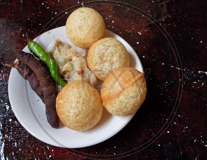 Panipuri Or Golgappa With Spicy Potato Stuff, Tamaarind And Chili In A Plate Isolated On Reddish Background With Copy Space, Also Known As Phuchka, Paani Patashi, Gol Gappa, Gup Chup