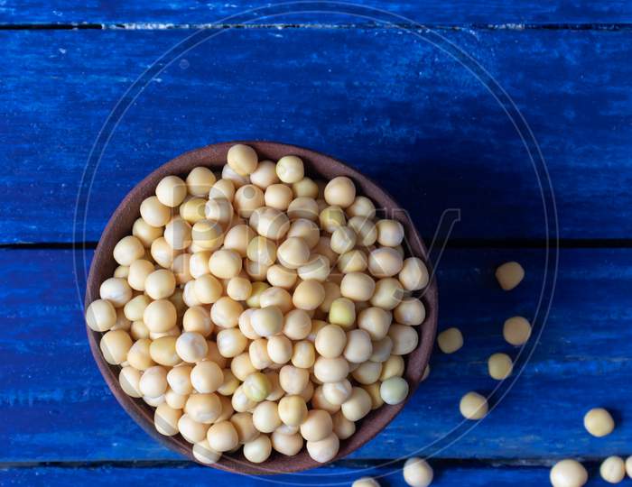 Top View Of Wet Pea Seeds In A Clay Bowl Isolated On Blue Wooden Background In Vertical Orientation