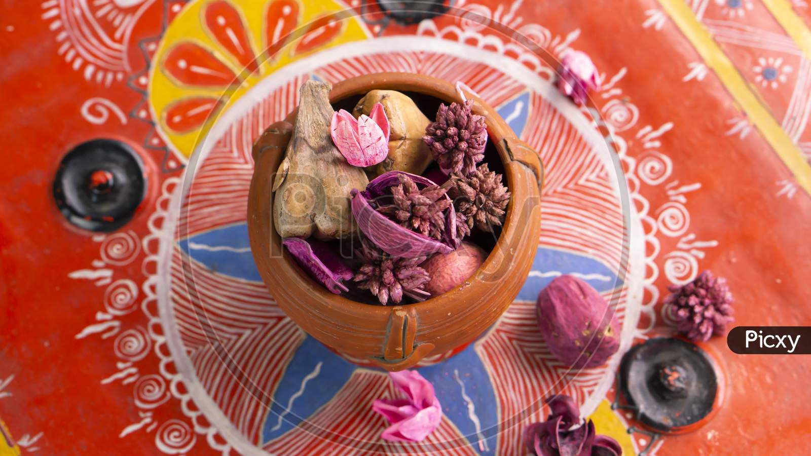 Dry petals on a clay pot on a red decorative background