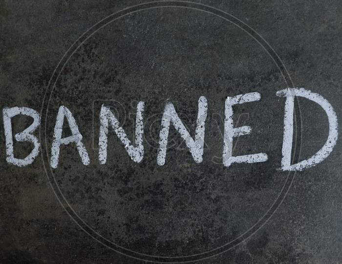 Banned Word Written On Blackboard With White Chalk