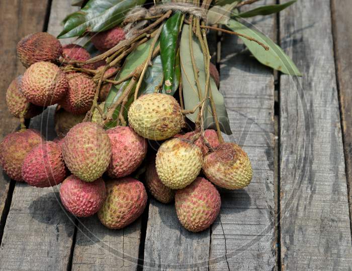 Organic Lychee Or Litchi Cluster With Leaves Isolated On Wooden Background
