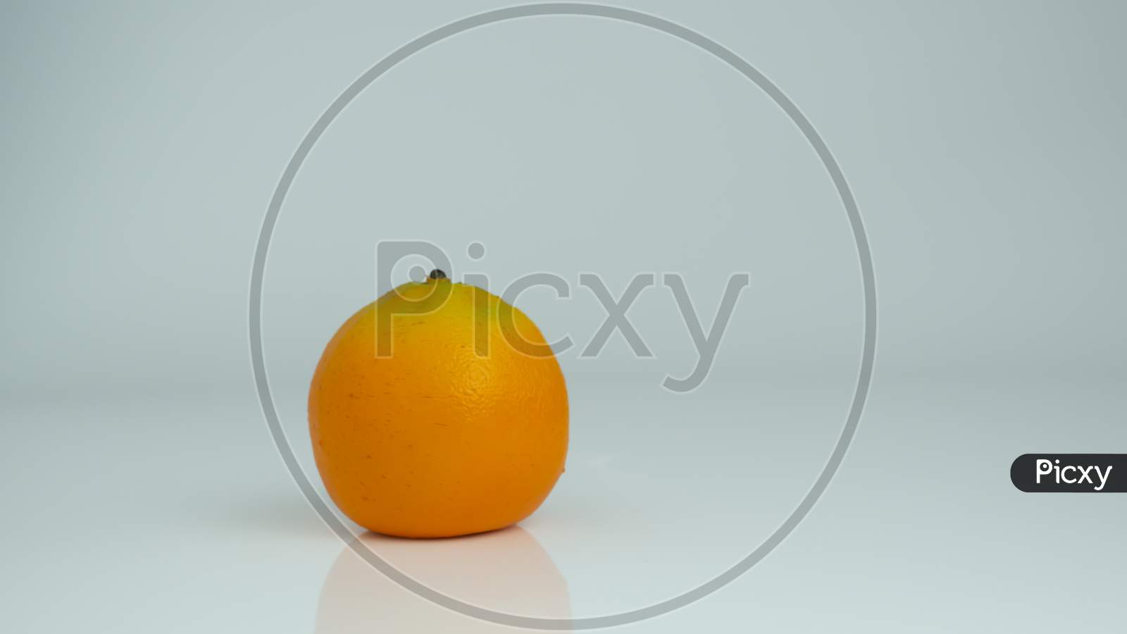 A jar with orange juice with a whole orange kept beside on an isolated background