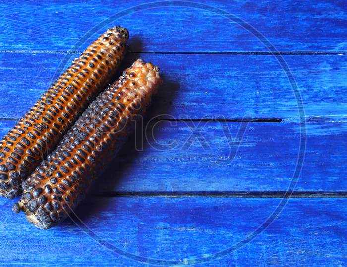 Roasted Maize Or Corn Isolated On Blue Colored Wooden Background With Copy Space