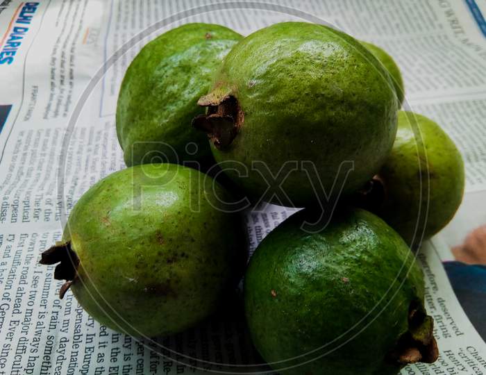 Raw guavas (Psidium guajava) on a piece of paper.