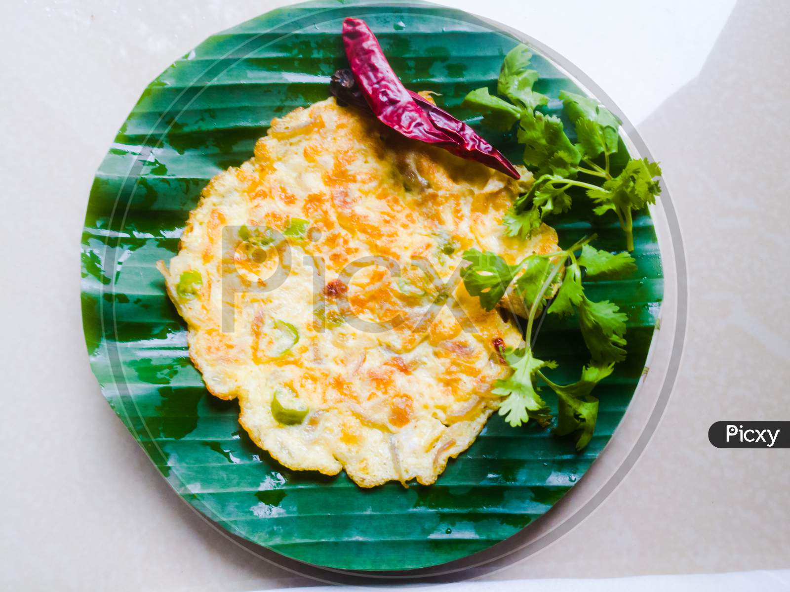 Egg Omelette With Coriander Leaves And Red Chillies In A Banana Leaf