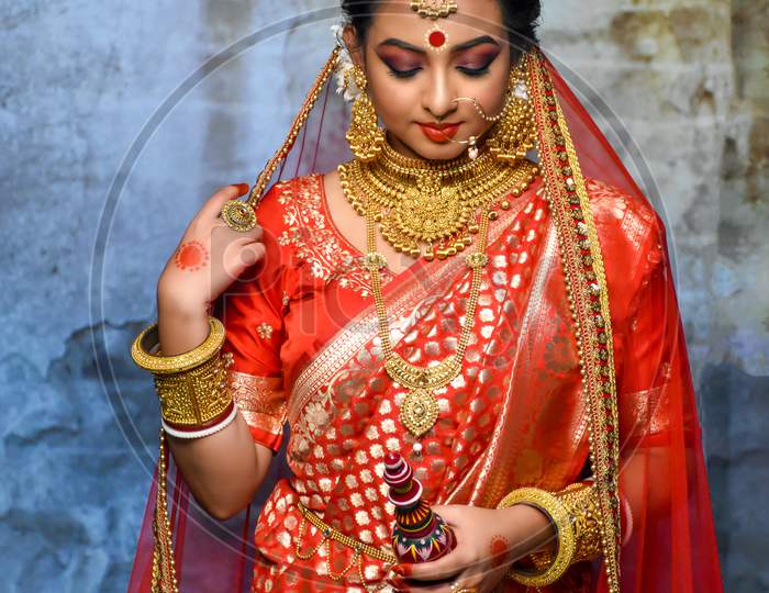 Stunning Indian Bride Dressed In Hindu Red Traditional Wedding Clothes Sari Embroidered With Gold Jewellery And A Veil Smiles Tender In A Banquet Hall In Kolkata On January 2020