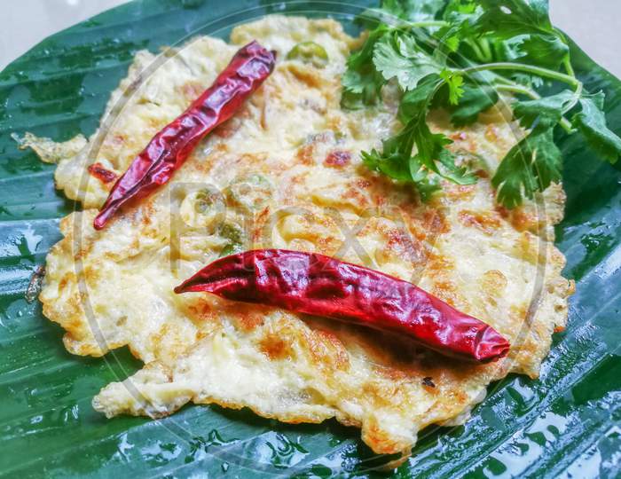 Egg Omelette With Coriander Leaves And Red Chillies In A Banana Leaf.
