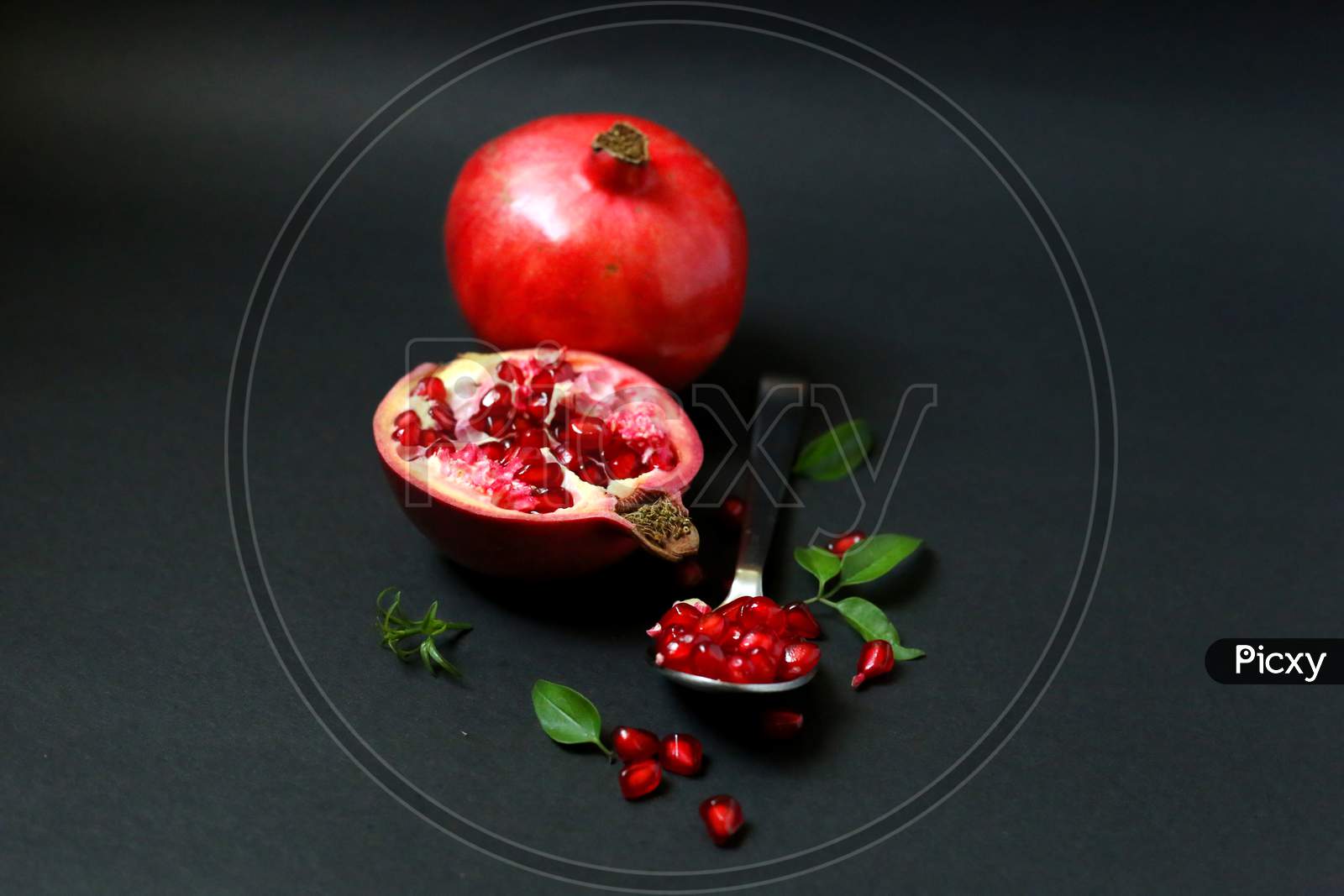 Ripe Pomegranate With Leaves On A Dark Background