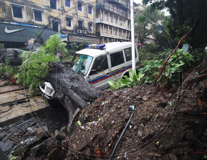 A police vehicle gets damaged after an uprooted tree fell on it after heavy rainfall in Mumbai, India on August 6, 2020.