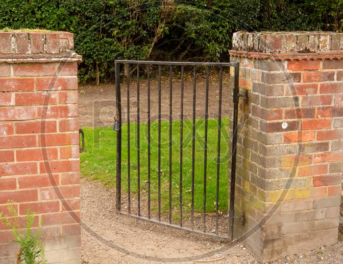 Open Wrought Iron Gate Between Two Brick Pillars