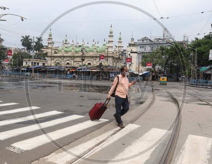 A man crosses a street that wears a deserted look amid the complete bi-weekly lockdown imposed by the government to curb Coronavirus spread in Kolkata on August 8, 2020