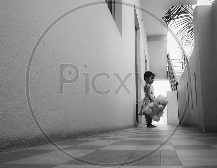 Long View Of Child Playing With Toy Alone In Floor B&W Image