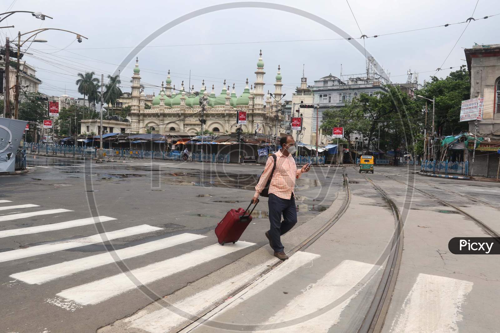 A man crosses a street that wears a deserted look amid the complete bi-weekly lockdown imposed by the government to curb Coronavirus spread in Kolkata on August 8, 2020