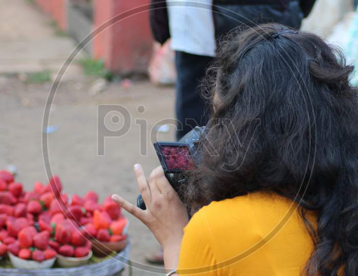 girl taking photograph of fresh Strawberries