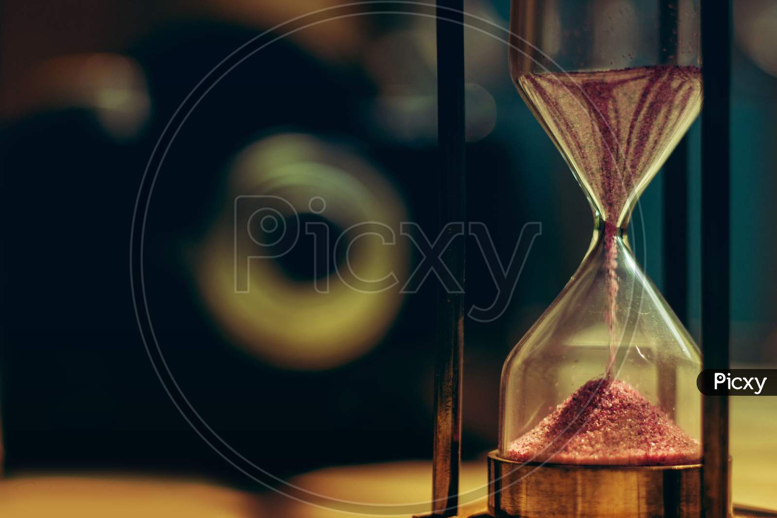 A sand hourglass in front of a vintage camera