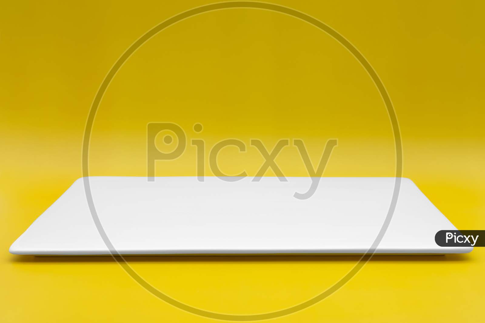 A Rectangle Empty White Plate Isolated On The Yellow Background.