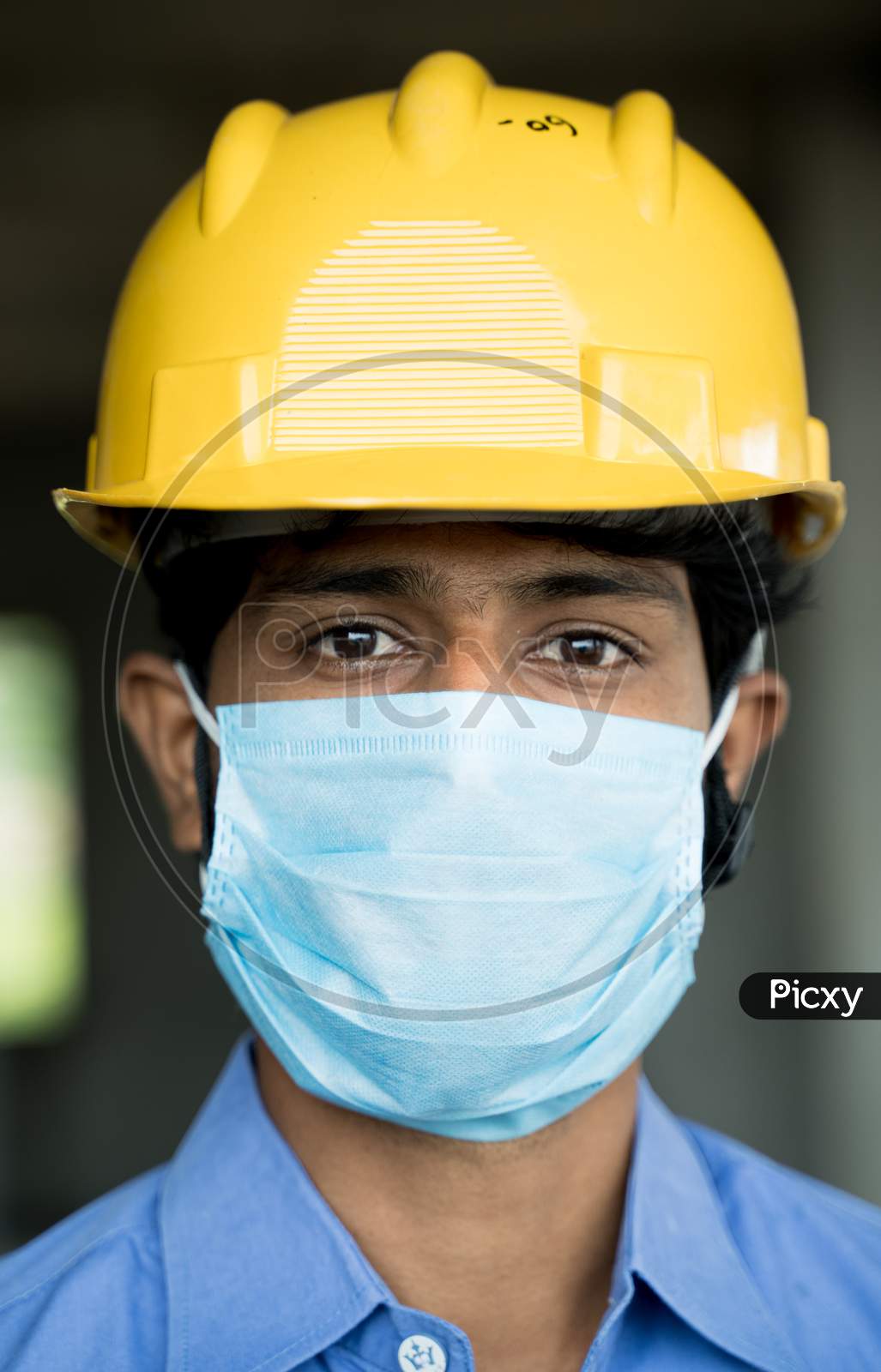 Head Shot Of Construction Worker, Reopening Of Construction Sites Or Industry - Construction Worker In A Construction Helmet With Medical Mask Due To Coronavirus Or Covid-19 Pandemic.
