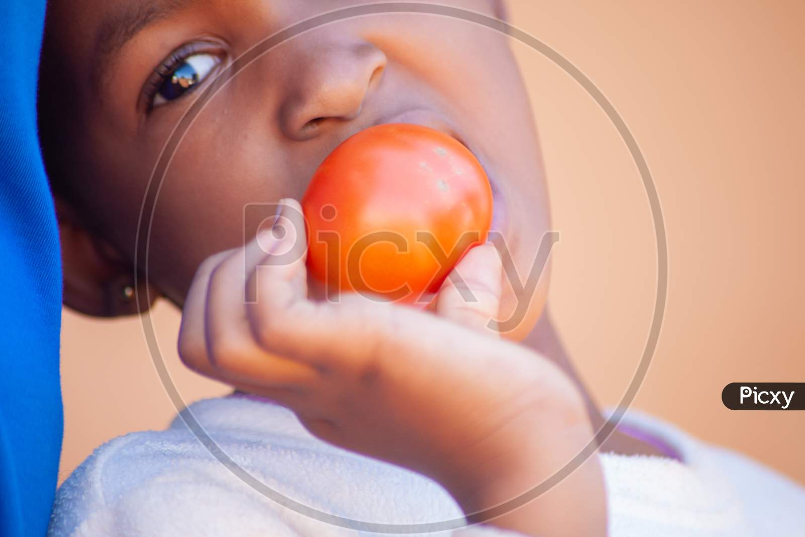 An African Child Eating A Red Ripe Tomato.Macro