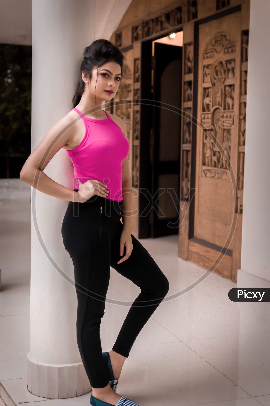 Shantiniketan, India. Fashion Portrait Of Beautiful Indian Young Girl Standing Beside A Pillar, Wearing A Pink Western Dress. Indian Lifestyle And Fashion. September 2019